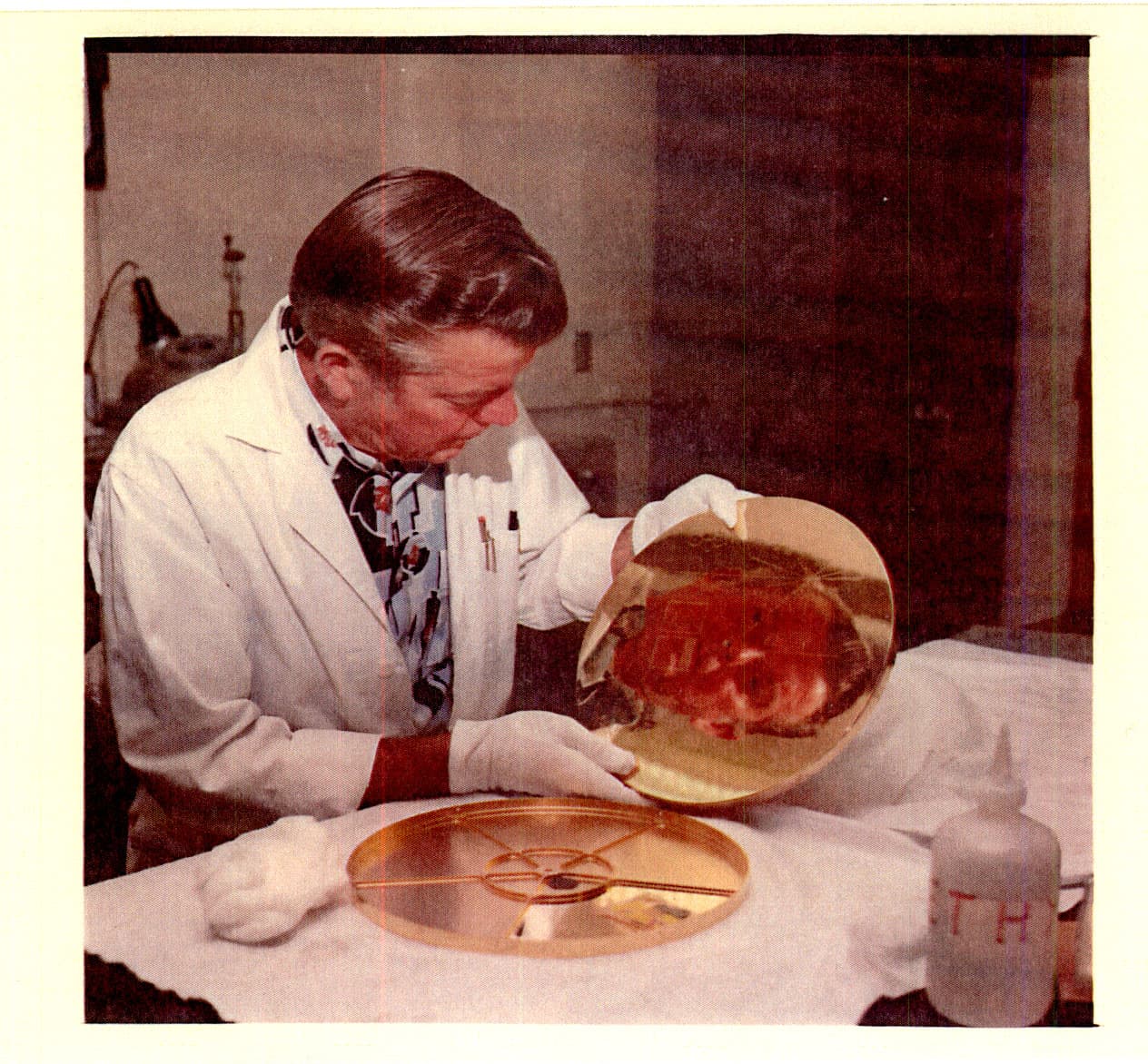 A technician inspecting a reflective Voyager Golden Record in a laboratory