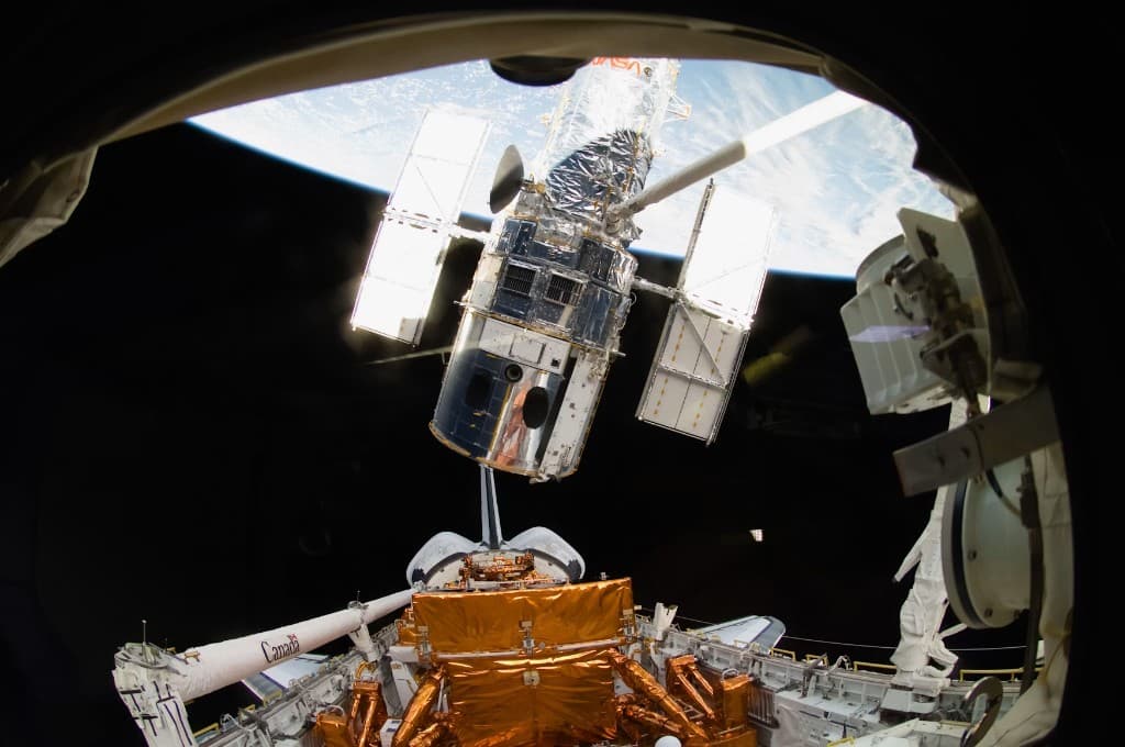 Hubble Space Telescope in the shuttle cargo bay above Earth