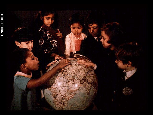 Children gathered around a terrestrial globe